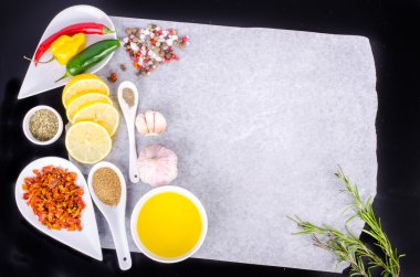 Cooking ingredients. Lemon, olive oil, herbs, salt, pepper on paper. Black background. Healthy food concept. Food frame