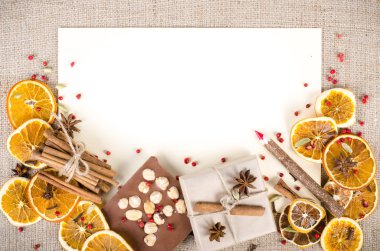Dried oranges, cinnamon, cloves, cardamom, handmade milk chocolate with nuts, wooden pencil, list of paper on sackcloth, canvas. Christmas, New Year and winter. Free space for your text.
