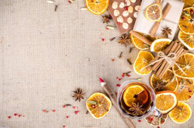 Dried oranges, cinnamon, cloves, cardamom, handmade milk chocolate with nuts, mulled wine, wooden pencil, list of paper on sackcloth, canvas. Christmas, New Year and winter. Free space for your text.