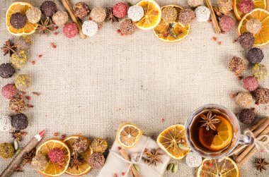 Handmade chocolate candies collection, dried oranges, spices, mulled wine, wooden pencil on wooden background. Christmas, New Year and winter. Free space for your text.