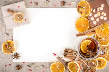 Dried oranges, cinnamon, cloves, cardamom, handmade milk chocolate with nuts, mulled wine, wooden pencil, list of paper on sackcloth, canvas. Christmas, New Year and winter. Free space for your text.