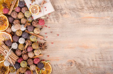 Handmade chocolate candies collection, dried oranges, cinnamon, cloves, cardamom on wooden background. Free space for your text.