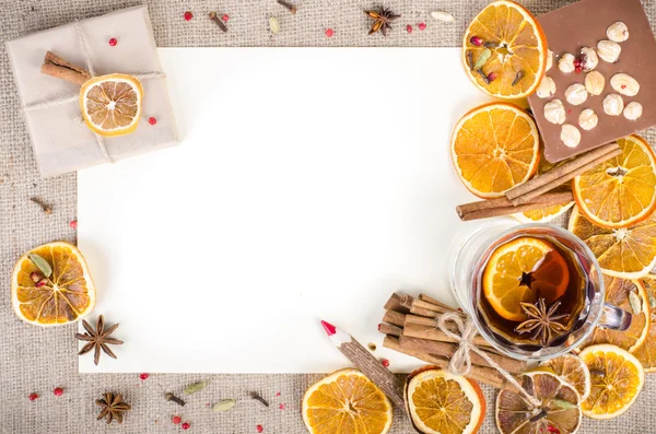 Dried oranges, cinnamon, cloves, cardamom, handmade milk chocolate with nuts, mulled wine, wooden pencil, list of paper on sackcloth, canvas. Christmas, New Year and winter. Free space for your text.