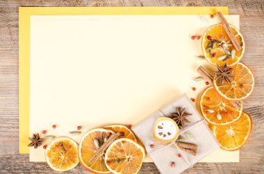 Dried oranges, cinnamon, cloves, cardamom, handmade milk chocolate in rustic packing, mulled wine on yellow and wooden background. Christmas, New Year and winter. Free space for your text.