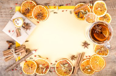 Dried oranges, cinnamon, cloves, cardamom, handmade milk chocolate in rustic packing, mulled wine on yellow and wooden background. Christmas, New Year and winter. Free space for your text.