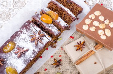 Chcolate spices cake with star anise and dried fruits, cinnamon, cloves, cardamom, handmade milk chocolate with nuts on sackcloth, canvas. Christmas gift.