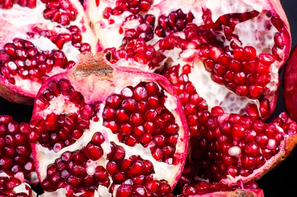 Granada jugosa roja, entera, mitad, fruta madura y quebrada sobre fondo negro . — Foto de Stock