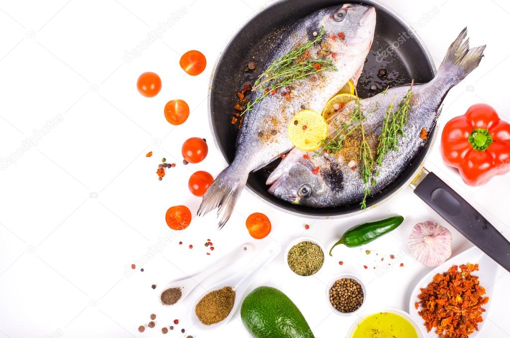 Fresh raw gilthead fishes with lemon, herbs, salt on white background. Healthy food concept. Food frame. Free space for your text.