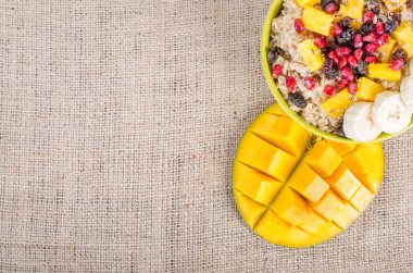 Mango, muz, nar, Kuru üzüm, Kuru meyve ve tuval, çul arka plan üzerine susam tohumu yulaf ezmesi. Sağlıklı vejetaryen kahvaltı. 