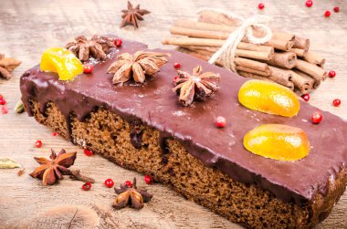 Çikolata baharat yıldız anason ve kurutulmuş meyveler, tarçın, karanfil, kakule ahşap zemin üzerine pasta. Noel hediyesi.