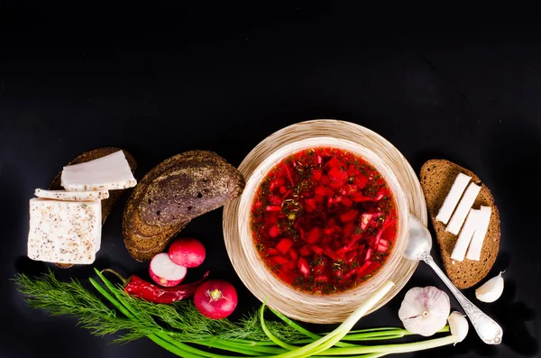 Beetroot soup in bowl with salted fresh lard, garlic, green onion, red pepper and rye bread on black background. — Stock Photo, Image