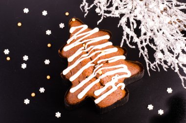 Noel ağacı şeklinde bisküvi ve siyah arka plan üzerinde karlı çelenk. Metniniz için boş alan.