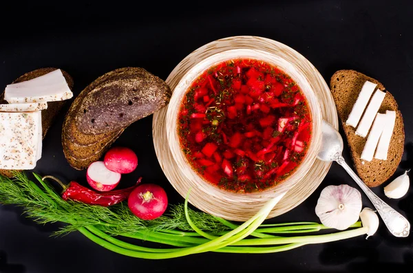Ukrainian beetroot soup - borscht in bowl with salted fresh lard - salo, garlic, green onion, red pepper and rye bread on black background. — Stock Image Ukrainian beetroot soup - borscht in bowl with salted fresh lard - salo, garlic, green onion, red pepper and rye bread on black background. Stock Photo