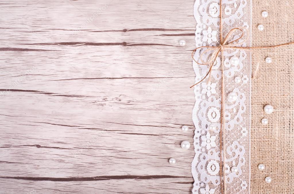 Lace, pearls, bowknot, canvas, sackcloth on wooden background. Rustic design. Free space for your text