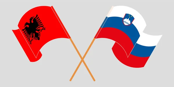 Bandeiras cruzadas e onduladas da Albânia e da Eslovénia — Vetor de Stock