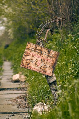 Eski paslı demiryolu tabelası ormanın arka planında