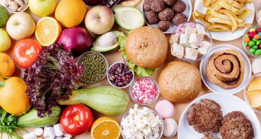 Meyve ve sebzeler tatlılara karşı ve fast food üst görünümü düz portakal arka planda yatıyordu