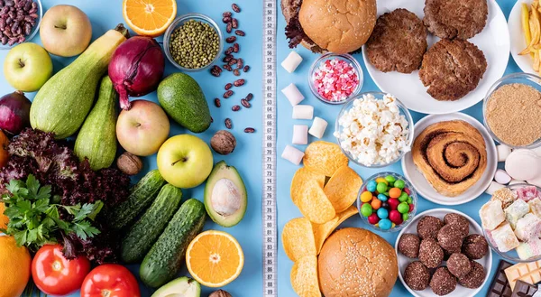 Fruit and vegetables vs sweets and fast food top view flat lay on blue background