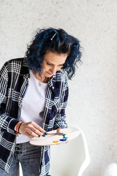 在工作室工作的创作性女画家在调色板上涂油画 — 图库照片