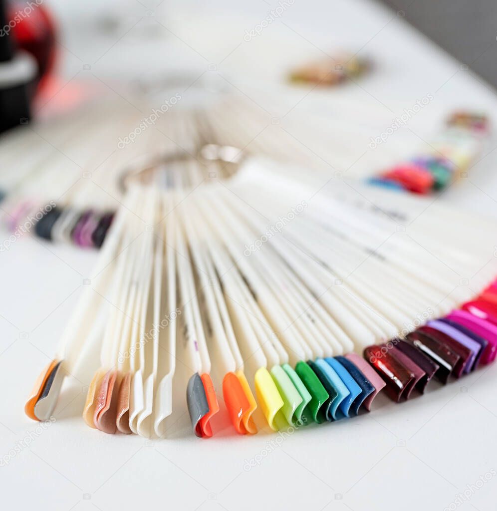 Colorful plastic nail tips with various nail designs on the table in manicure salon