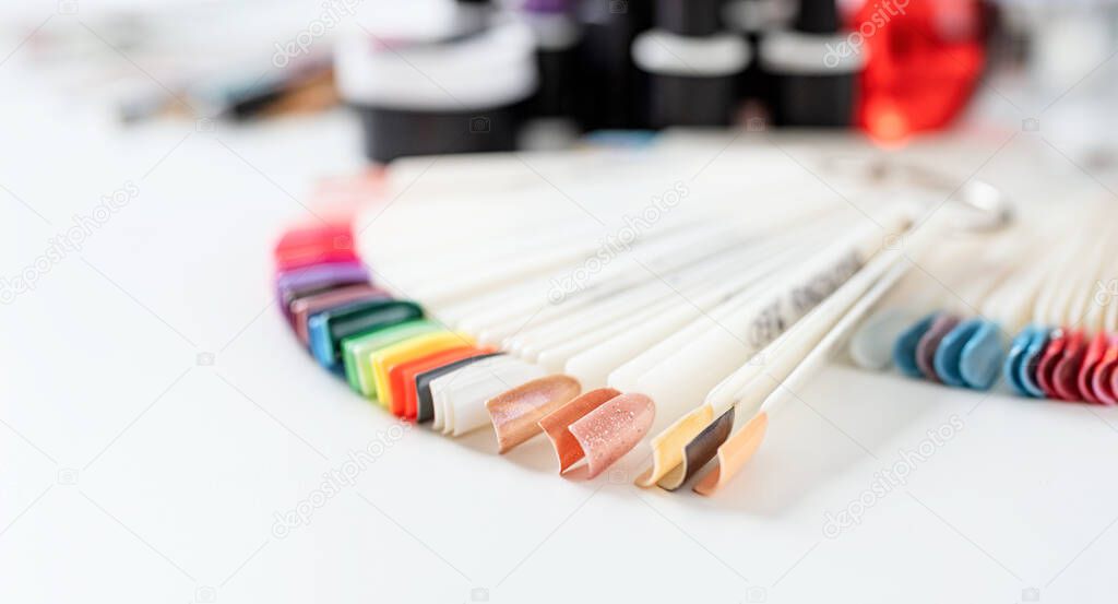 Colorful plastic nail tips with various nail designs on the table in manicure salon