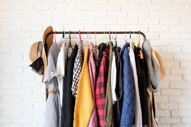 Beyaz tuğla duvarda asılı renkli elbiselerle dizilin.