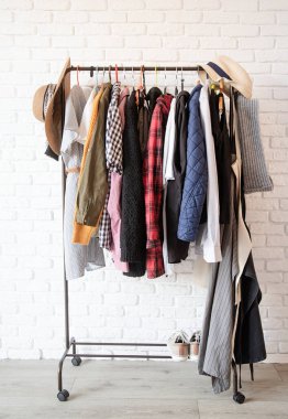 Beyaz tuğla duvarda asılı renkli elbiselerle dizilin.