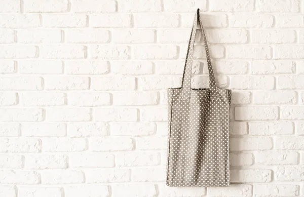 Mock up gray dotted tote bag eco hipster white cotton fabric on white brick wall background. Copy space