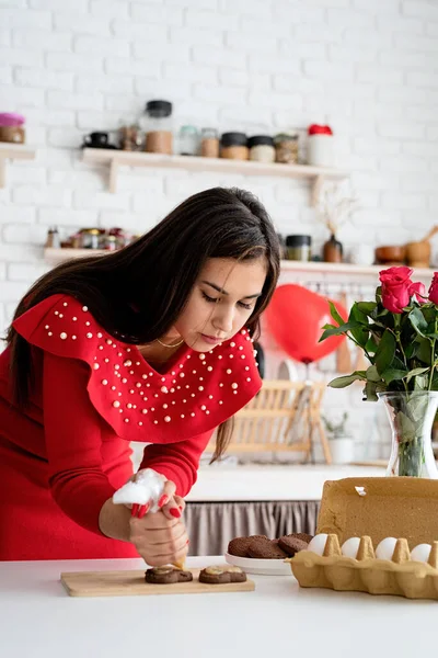 Жінка в червоній сукні робить валентинкове печиво на кухні — стокове фото