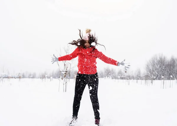 Jovem morena despreocupada mulher em camisola vermelha pulando na neve ao ar livre — Fotografia de Stock