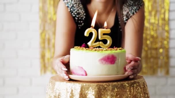 Щаслива молода жінка, яка дме свічку на день народження, святкуючи свій 25-й день народження вдома . — стокове відео