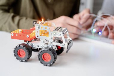 Çocuklar atölyede robot araba yaparken eğleniyorlar.