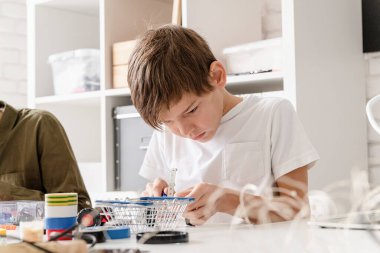 Genç çocuklar atölyede robot arabaları yaparken eğleniyorlar.