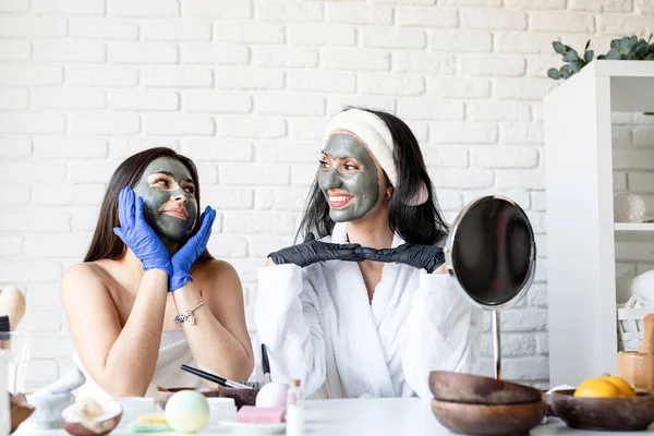 Dua wanita cantik dalam sarung tangan menerapkan masker wajah bersenang-senang — Stok Foto