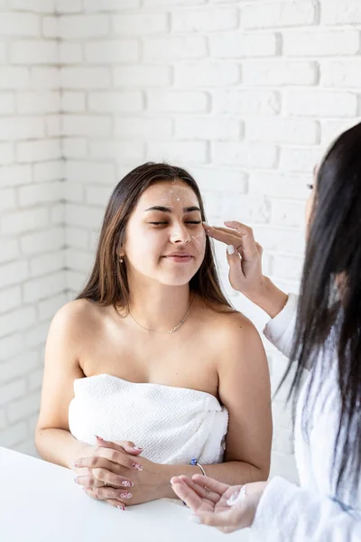 Dua wanita cantik menerapkan krim wajah melakukan prosedur spa — Stok Foto