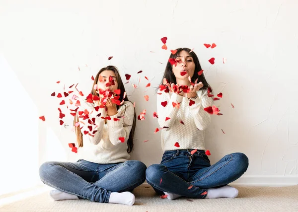 Dois Melhores Amigos Divertindo Casa Soprando Forma Coração Vermelho Confetti — Fotografia de Stock