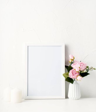 Duvardaki beyaz çerçeveyi şakayık ve beyaz mumlarla süsleyin.