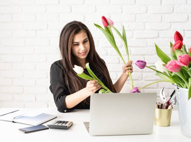 Küçük işletme konsepti. İnternette müşteriyle birlikte çalışan genç bir çiçekçi buket için çiçek seçiyor.