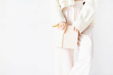 Rahat ev kıyafetleri içindeki güzel seksi kadın açık bir kitap tutuyor.