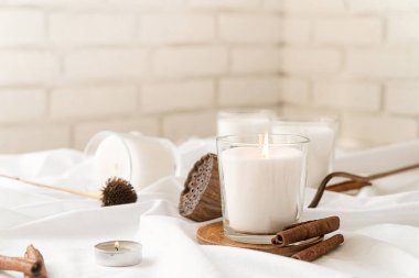 Ev dekorasyonu ve iç dekorasyon. Tarçınlı yanan mumlar ve beyaz kumaş arka planda kuru çiçekler.