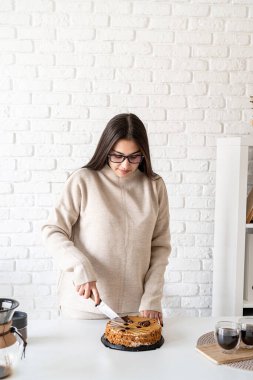 Alternatif kahve demleniyor. Kahve demliğinde kahve hazırlayan ve kek kesen genç bir kadın.