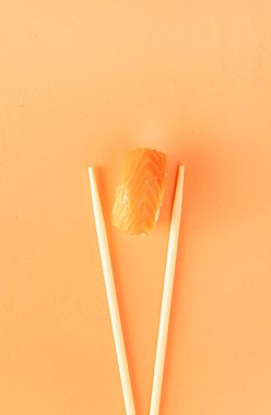 Minimum konsept. Somon ve çubuklu suşi, turuncu arka planda izole edilmiş. Üst Manzara. Düz yatıyordu