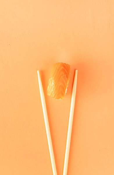 Минимальная концепция. суши с лососем и палочками, изолированные на оранжевом фоне. Вид сверху. Плоский лежал