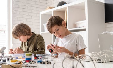 Genç çocuklar atölyede robot arabaları yaparken eğleniyorlar.
