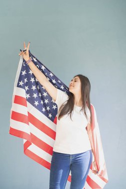 Mavi arka planda Amerikan bayrağı olan güzel genç bir kadın.