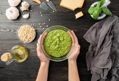 Adım adım İtalyan pesto sosu pişiriyorum. 8. adım: Tüm malzemeleri karıştırmak. Pesto sosu hazır. Taze yeşil fesleğen, parmesan peyniri, fındık, zeytinyağı ve siyah ahşap masa üzerinde sarımsak.