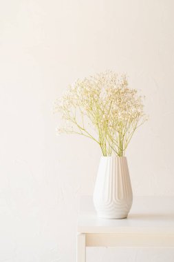 Masada beyaz vazodaki beyaz çigila çiçekleri, minimal stil, boşluğu kopyala
