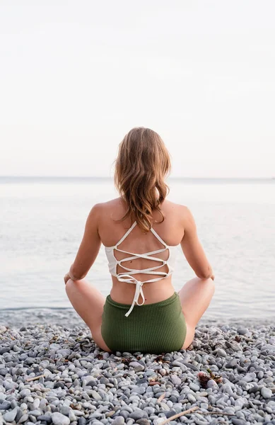 ビーチで瞑想水着の若い女性のリアビュー — ストック写真