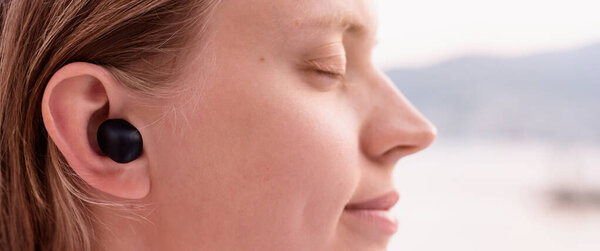 Технологическая концепция. Женщина с беспроводными наушниками, море на заднем плане, баннер