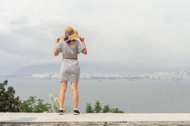 Yazlık elbiseli genç bir kadının şehir manzarasına bakışı. Özgürlük kavramı. Seyahat kavramı